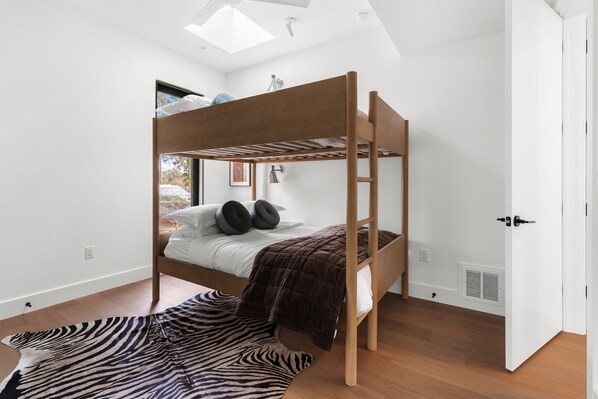 A bunk bed with a skylight, a zebra-patterned rug, and a white door.