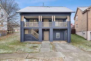 Ein zweistöckiges Wohnhaus mit Veranda, einer Treppe, die zum oberen Stockwerk führt, und einer Garage.