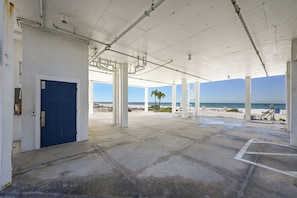 A covered outdoor area with a blue door, concrete flooring, and a view of the beach and ocean. - Beachfront Escape at Gulf Breeze Unit D! (Bradenton Beach)