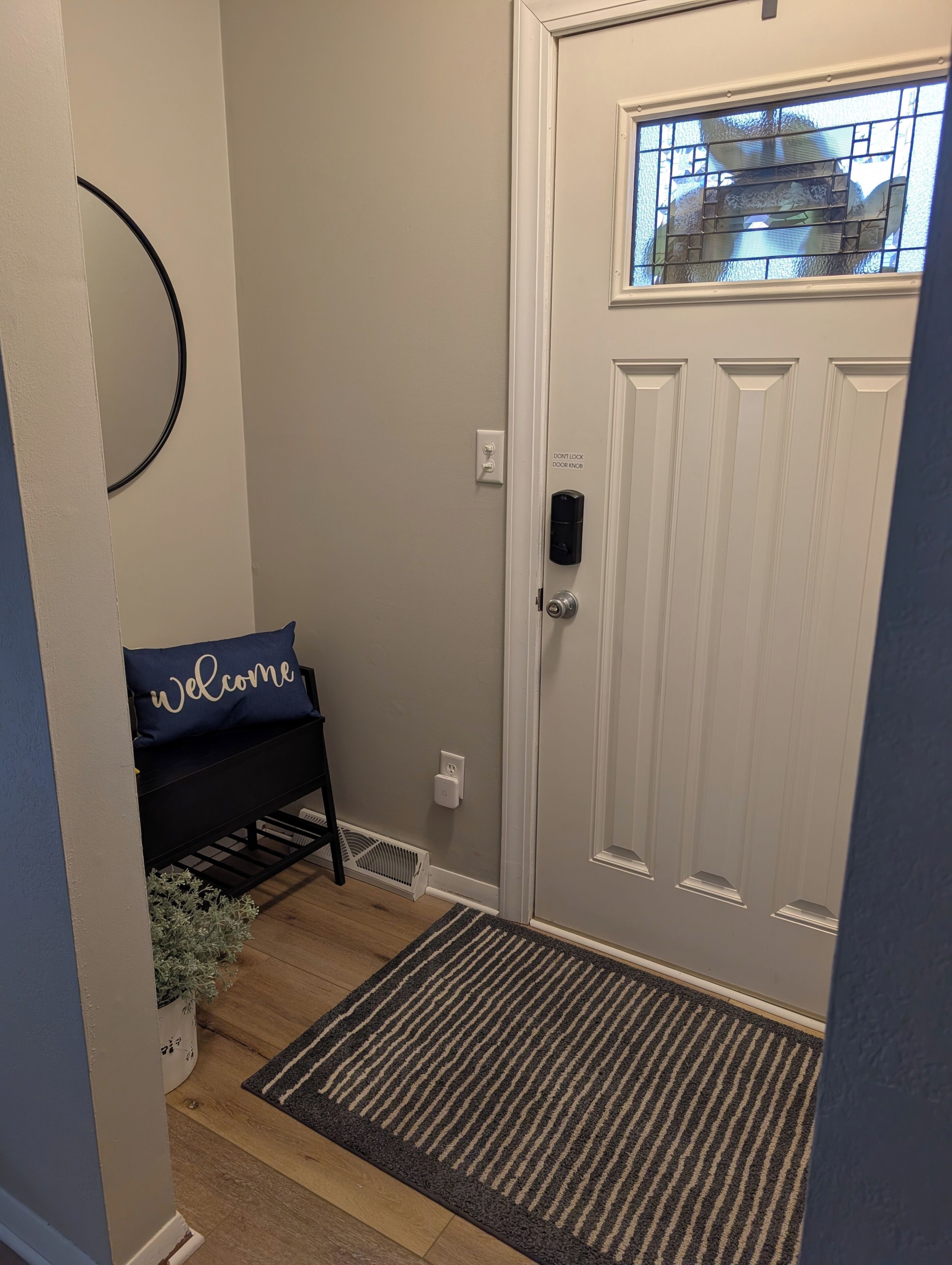 A door with a 'Welcome' sign, a doorknob, and a window with a grid pattern.