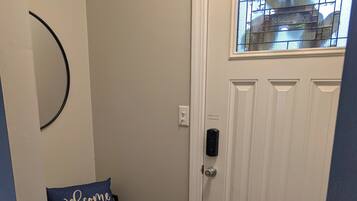 A door with a 'Welcome' sign, a doorknob, and a window with a grid pattern.