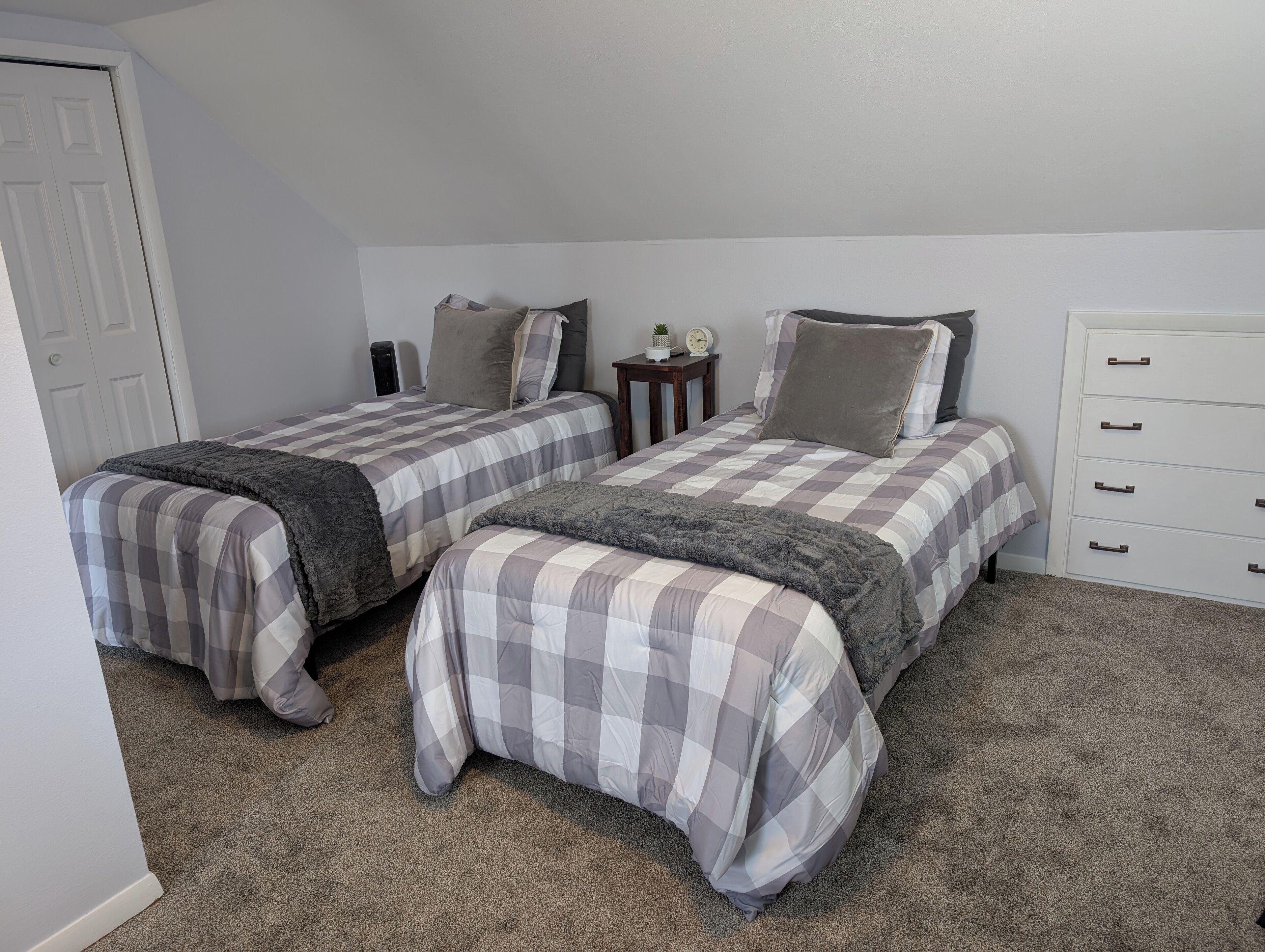 Un dormitorio con dos camas, un aparador y una mesita de noche.