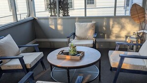Un espace extérieur abrité, aménagé avec des chaises confortables et une table ronde, agrémenté d'un élément décoratif central.