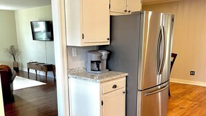 Eine kompakte Küche mit integriertem Kühlschrank, einer Kaffeemaschine und Holzboden.