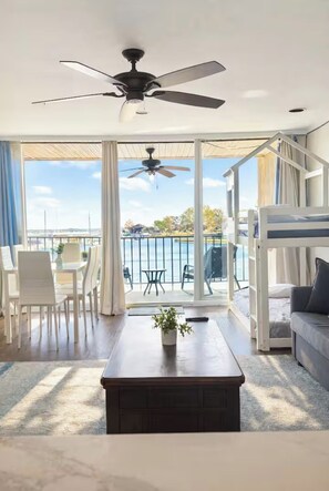 A balcony with a view of the sea, a ceiling fan, and a dining area with white chairs and a table. - Conroe Waterfront Retreat & Luxury Resort Setting (Montgomery)