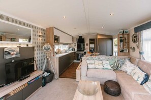 Ein kompakter Wohnraum mit Küchenzeile, einer Couch, einem Couchtisch und einem Fernseher.