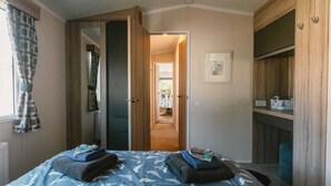 A bedroom with a bed, a wardrobe, and a door leading to a hallway. - 'Serenity' A Tranquil & Peaceful Retreat set in a Cornish country park (Relubbus)