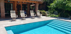 Une piscine avec des chaises longues et un espace patio couvert.