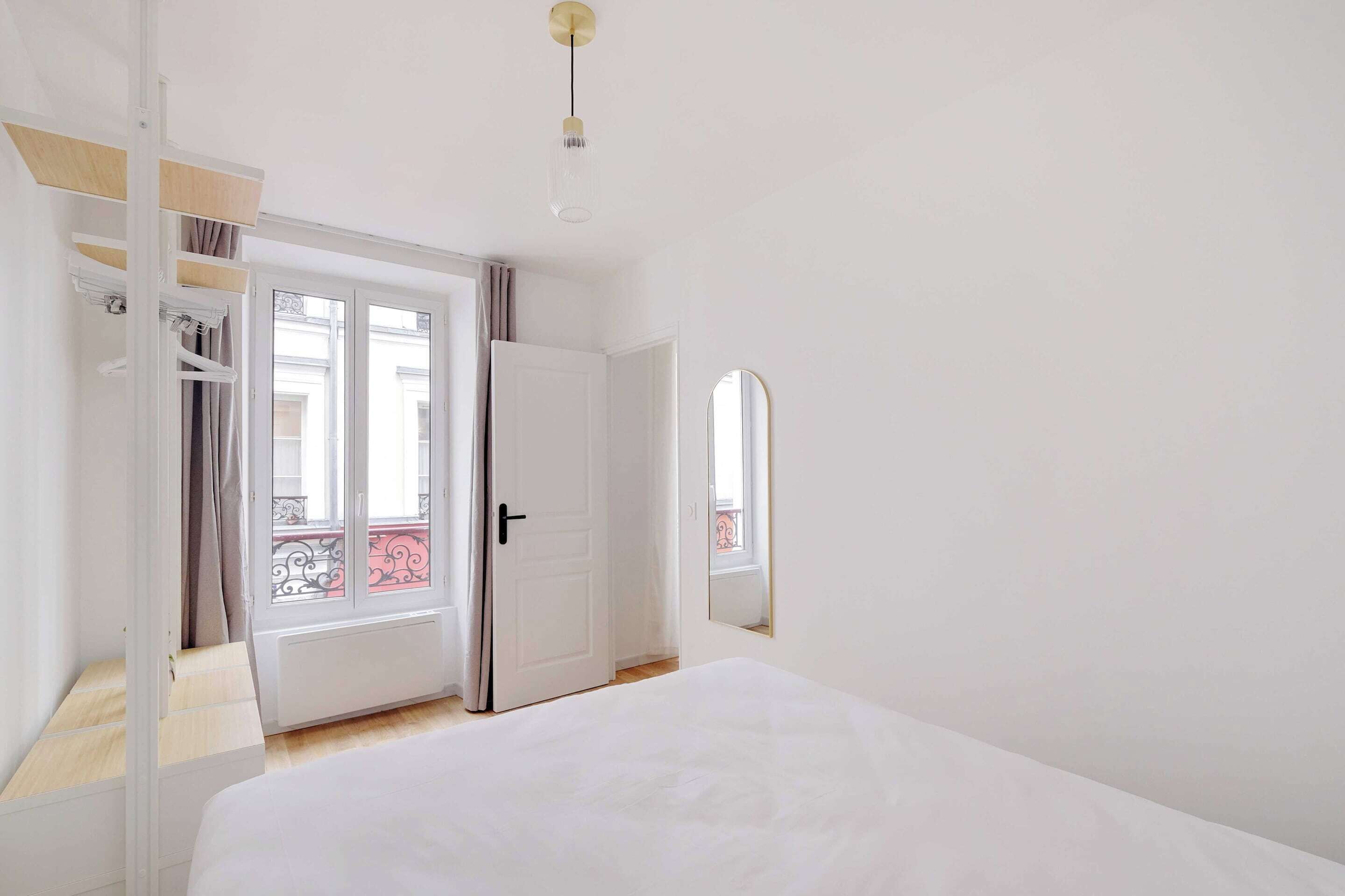 A bedroom with a bed, a wardrobe, a door, and a window.