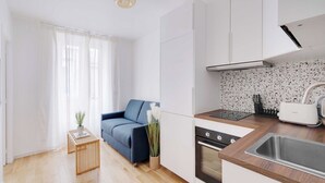 A modern kitchen with white cabinets, a wooden countertop, and a stainless steel sink. - Charming Apartment 1br/3p - Oberkampf (Paris)
