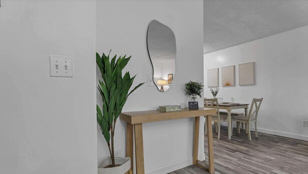 Un interior modern amb una taula consola de fusta, un mirall gran i una zona de menjador amb caires i taula.