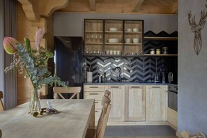 Una cucina moderna con piastrelle a spina di pesce, mobili in legno e un'area pranzo con tavolo apparecchiato per due.