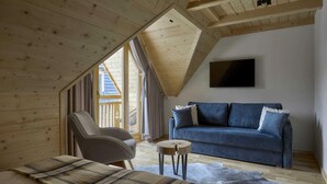 A cozy room with a sloped ceiling, a sofa, a chair, and a small round table.