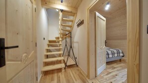 A wooden interior with a staircase leading to a loft bedroom.