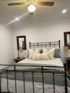 A neatly arranged bedroom with a bed, a ceiling fan, and two bedside tables with lamps. - Designer Cottage in the Woods • Hot Tub • Fireplace • Fire Pit • Near Lake (Cresco)