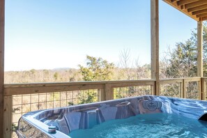 Ein Whirlpool mit einer Holzterrasse und Blick auf ein bewaldetes Gebiet.