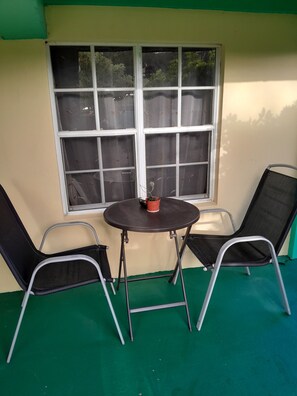 A room with a window, two chairs, a small table, and a potted plant.