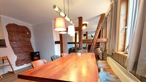 A spacious dining area with a long wooden table, modern pendant lights, and a rustic brick wall. - Bergstadthaus St. Andreasberg for families & friends, child-friendly & central (Sankt Andreasberg)