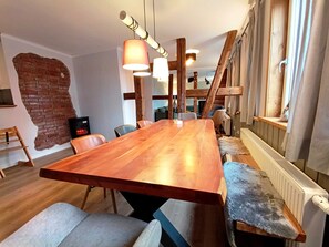A spacious dining area with a long wooden table, modern pendant lights, and a rustic brick wall. - Bergstadthaus St. Andreasberg for families & friends, child-friendly & central (Sankt Andreasberg)