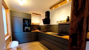 A modern kitchen with dark cabinetry, a wooden countertop, and a built-in oven. - Bergstadthaus St. Andreasberg for families & friends, child-friendly & central (Sankt Andreasberg)