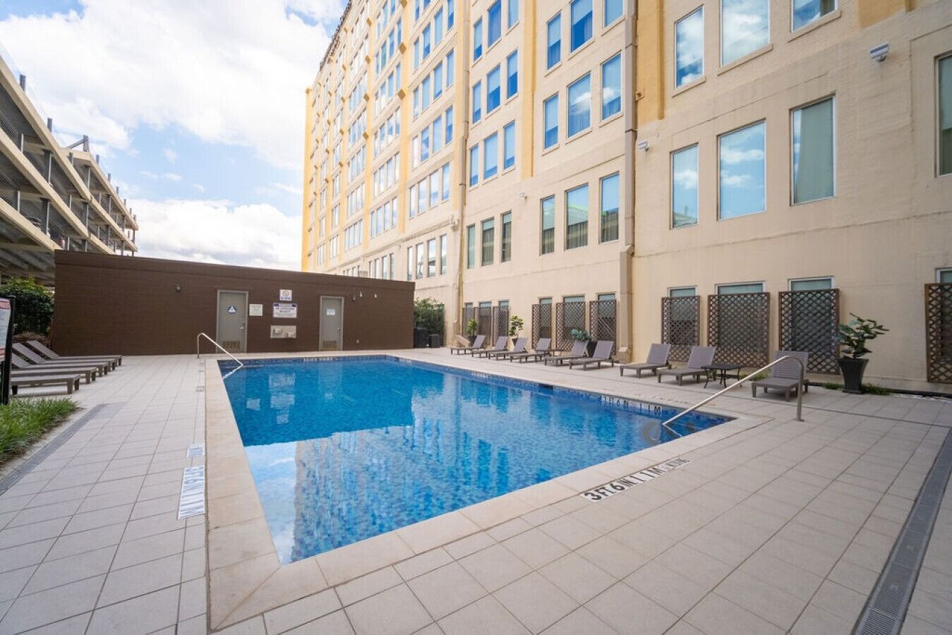 A swimming pool with lounge chairs and a building with multiple windows.