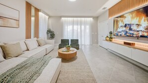 A modern living room with a sofa, a coffee table, and a TV. - 7BR house sleeps 18 with private pool (Clermont)