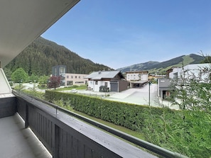 Ein Balkon mit Blick auf einen GebÀudekomplex, einen Parkplatz und eine Berglandschaft.
