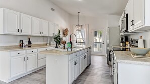 Una cocina amplia con armarios blancos, una isla grande y vistas al exterior.
