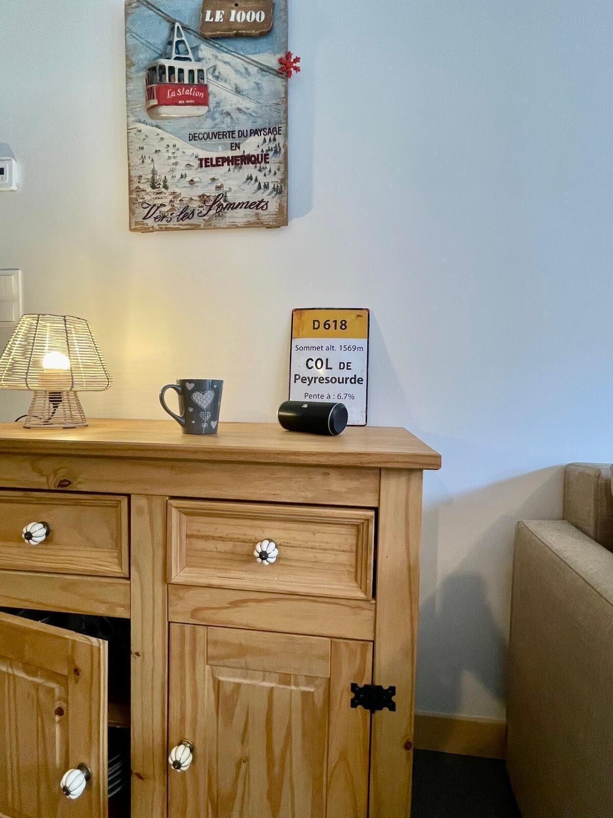 A wooden dresser with drawers, a lamp, a mug, and a sign indicating a mountain's altitude.