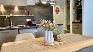 A modern kitchen with a dining area, including a wooden table, chairs, and a vase with flowers. - Gite Le 1000 Votre gîte à Loudenvielle - Comfort, nature and serenity (LOUDENVIELLE)