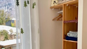 A room with a wooden wardrobe, a window with a view of a snowy landscape, and a curtain with tree decals. - Gite Le 1000 Votre gîte à Loudenvielle - Comfort, nature and serenity (LOUDENVIELLE)