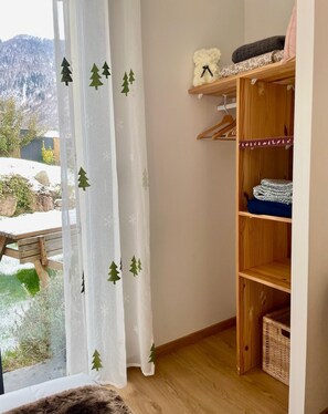 A room with a wooden wardrobe, a window with a view of a snowy landscape, and a curtain with tree decals. - Gite Le 1000 Votre gîte à Loudenvielle - Comfort, nature and serenity (LOUDENVIELLE)