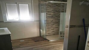 A bathroom with a shower, a window, and a wooden floor. - Cozy House in El Palmar for 4 Guests (Vejer de la Frontera)