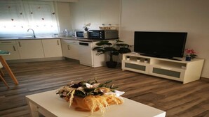 A modern kitchen with white cabinets, a microwave, and a coffee maker. There is a white table with a plant in the center of the room. - Cozy House in El Palmar for 4 Guests (Vejer de la Frontera)