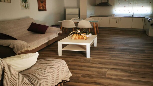 A living room with a sofa, a coffee table, and a kitchen in the background. - Cozy House in El Palmar for 4 Guests (Vejer de la Frontera)