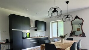 Eine moderne Küche mit dunklen Schränken, einem eingebauten Ofen und einem Essbereich mit Holztisch und Stühlen.