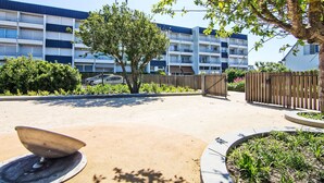A courtyard with a tree, a satellite dish, and a building with multiple balconies. - Kérabus by Interhome (Quiberon)