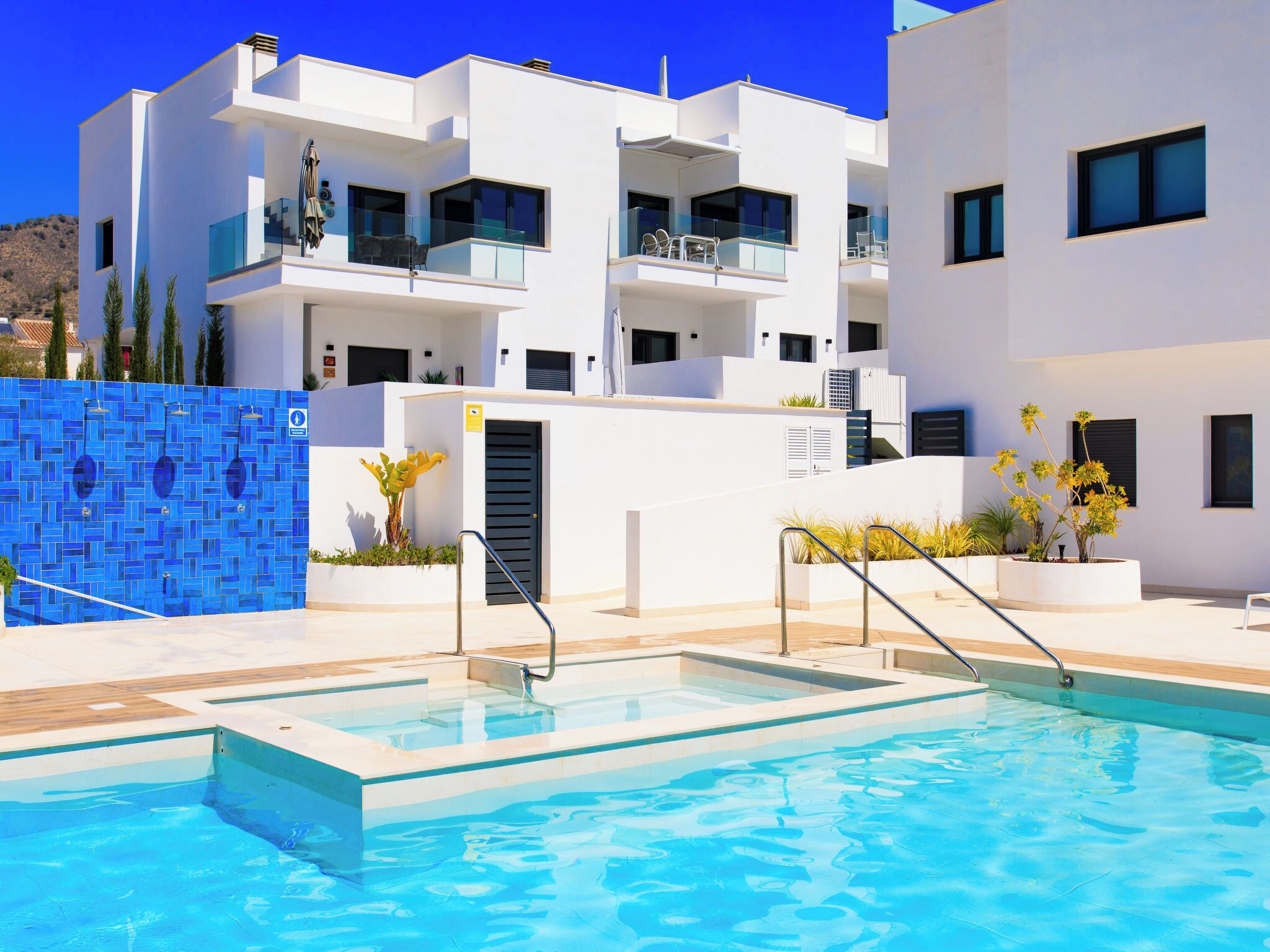 Um edifício moderno com piscina, com várias varandas e um céu azul límpido.