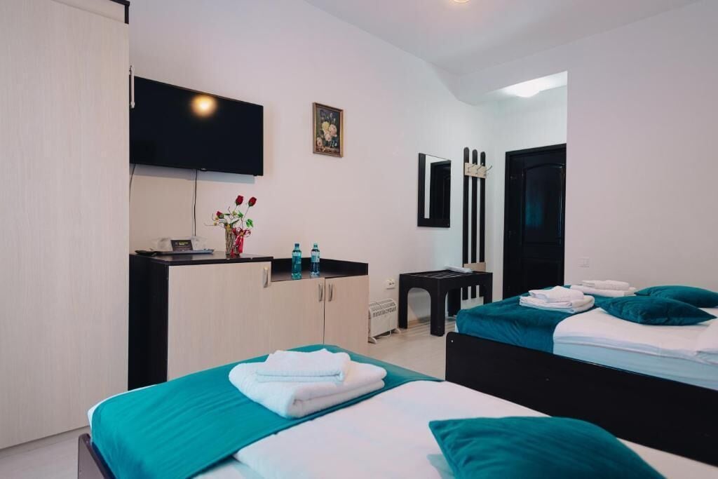 Habitaci ón de hotel con dos camas, un escritorio, un televisor de pantalla plana, una mesita y una puerta.