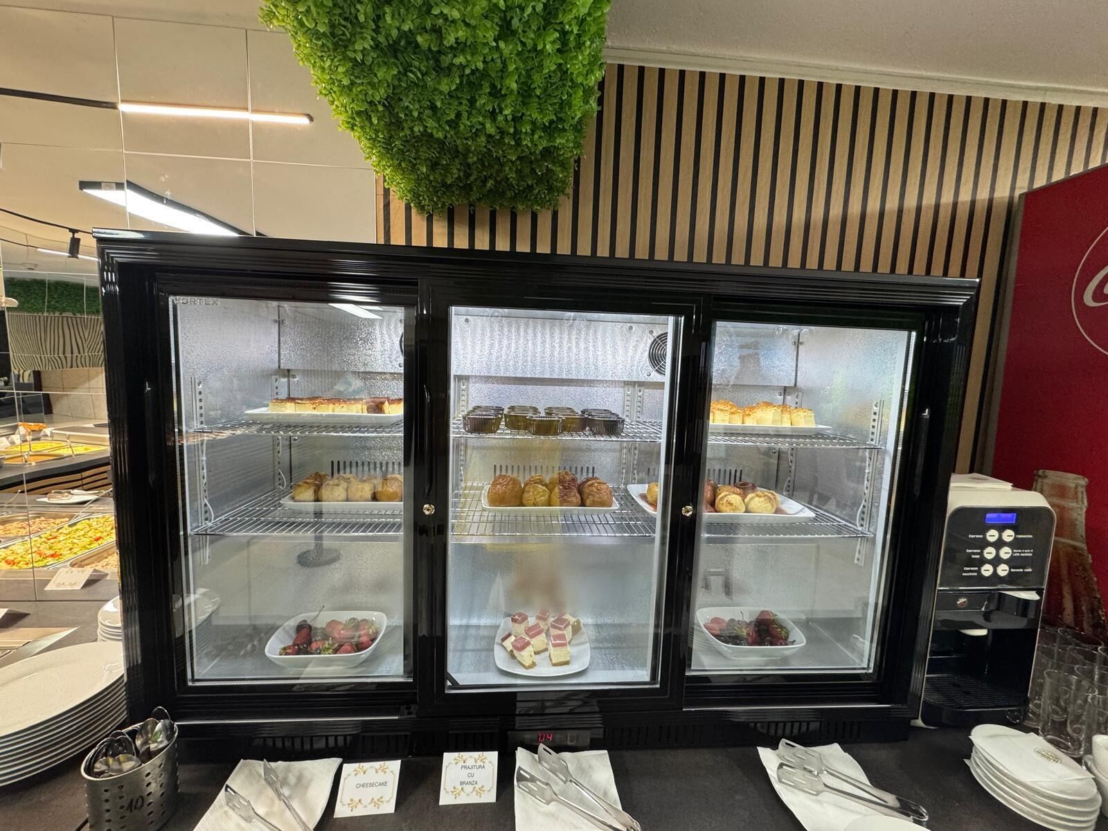 Una vitrina de pastelería con distintos productos horneados y una máquina de café.
