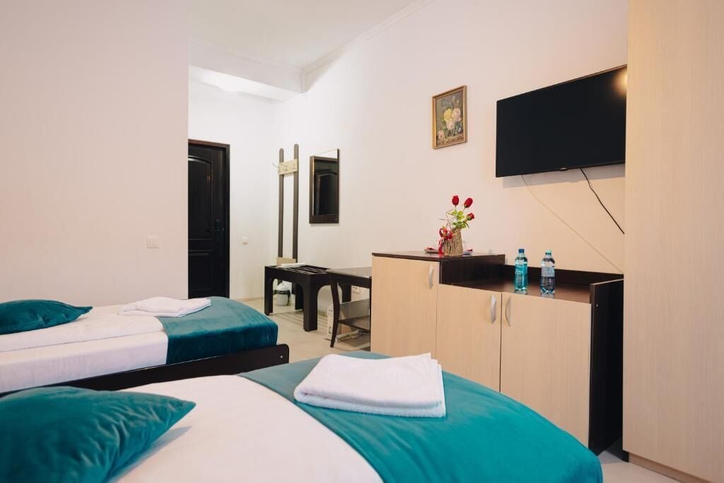 Habitación de hotel con dos camas, un escritorio, un televisor y un mueble con botellas de agua.