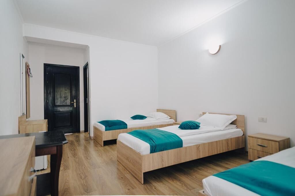 Ein modernes, minimalistisches Schlafzimmer mit zwei hölzernen Betten, einem kleinen Nachttisch und einem Schreibtisch.