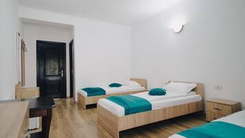 Ein modernes, minimalistisches Schlafzimmer mit zwei hölzernen Betten, einem kleinen Nachttisch und einem Schreibtisch.