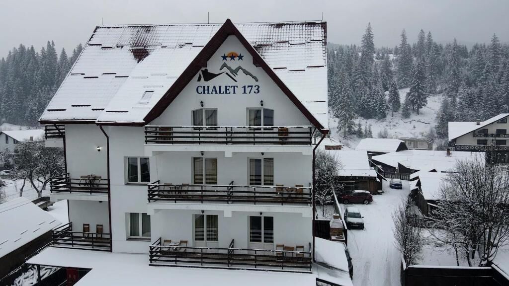 A multi-story building with a ski slope logo and the name "Chalet 173" on the facade.