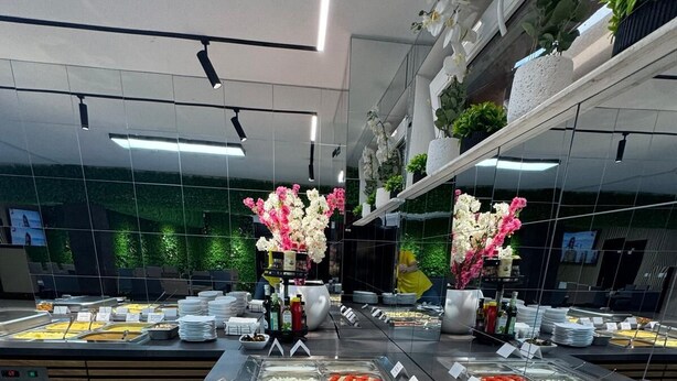 A buffet with various food options, a mirror reflecting the room, and a green wall with plants.