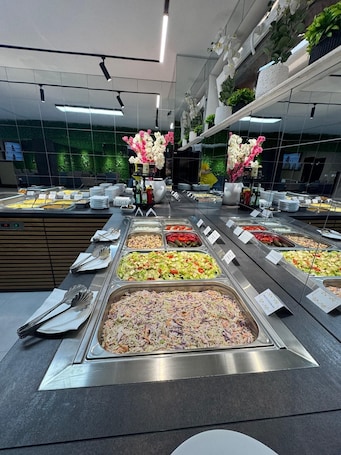 A buffet with various food options, a mirror reflecting the room, and a green wall with plants.. Chalet 173