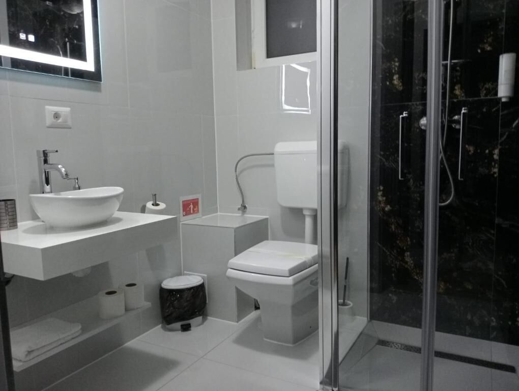 A modern bathroom with a white sink, toilet, and shower.