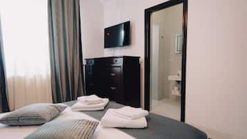 Ein Hotelzimmer mit einem Bett, einem wandmontierten Flachbildfernseher, einem Kleiderschrank und einem Spiegel.