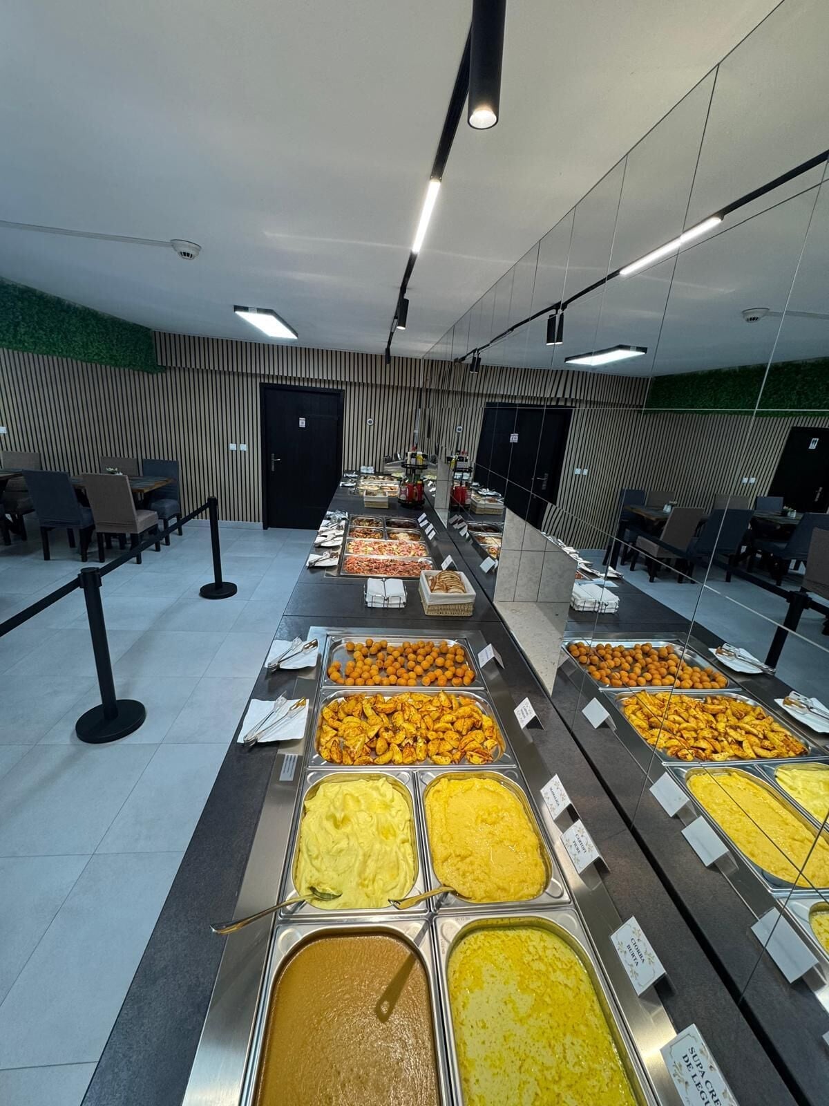 A buffet with various food options, a seating area with tables and chairs, and a modern interior design.