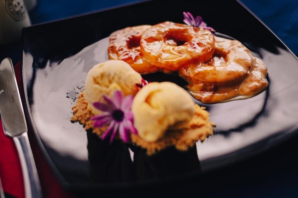 Un plato con rosquillas glaseadas y helado, acompañado de un cuchillo y una cuchara.